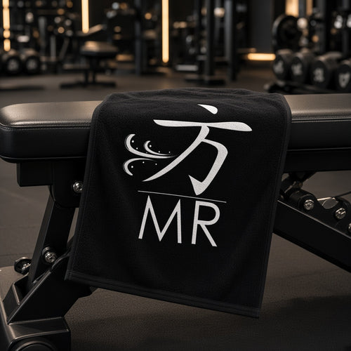 1 Moore Rep black gym sweat towel with white 方 MR logo draped over a weight bench in a dark gym